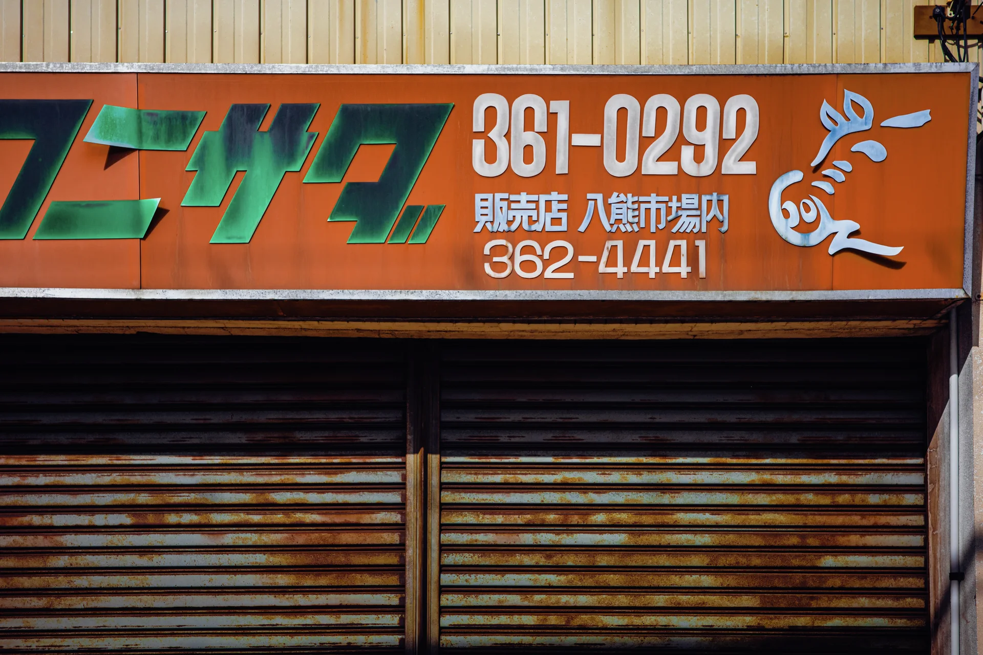 An orange sign with green lettering and a white rabbit motif sits above rusted metal shutters.