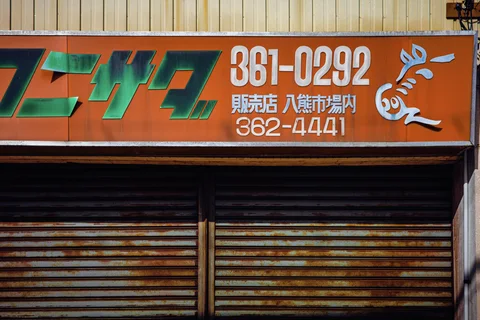 An orange sign with green lettering and a white rabbit motif sits above rusted metal shutters.