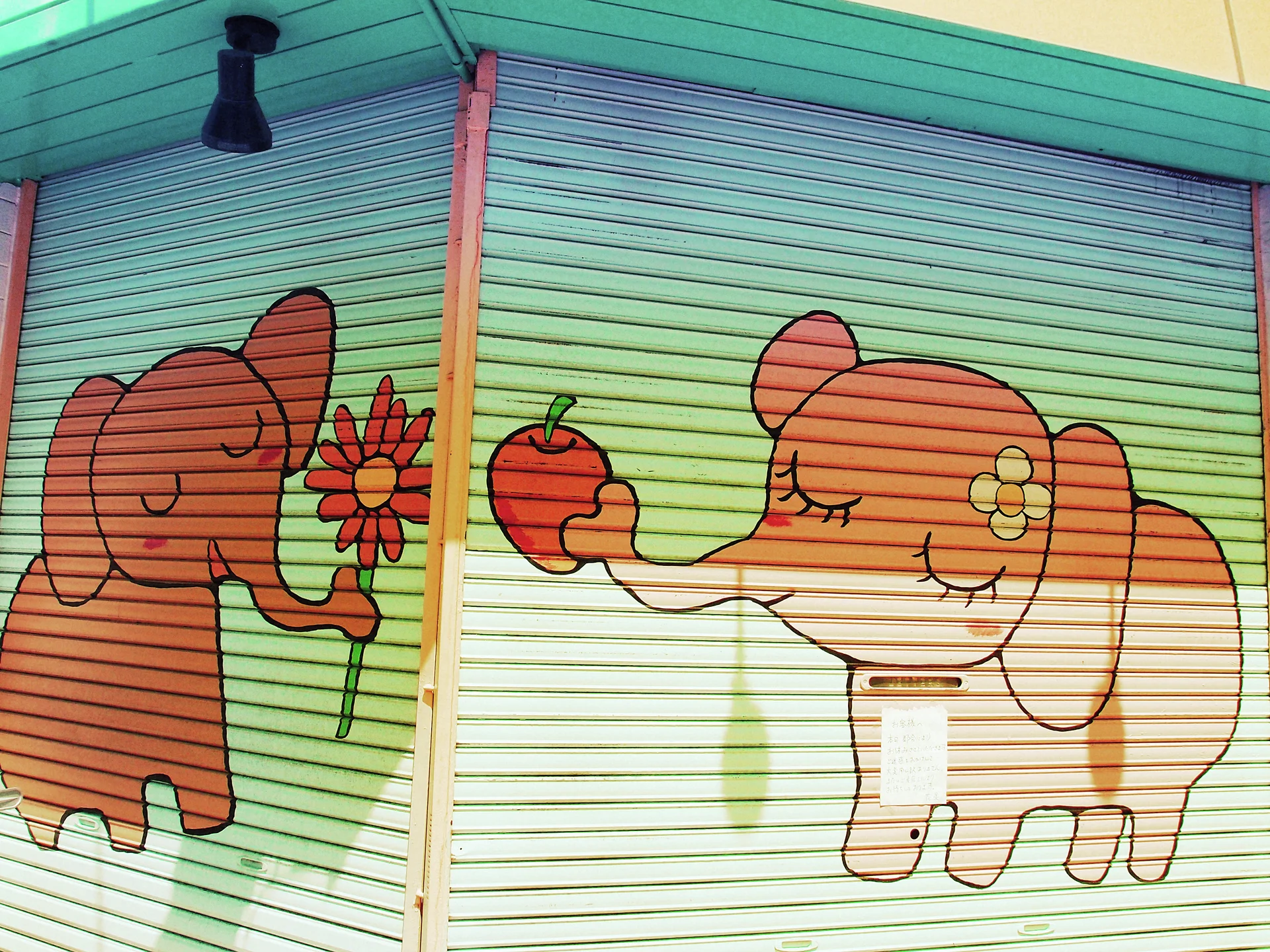 Cartoon elephants holding a flower and an apple decorate pale green corner shutters.