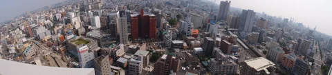 A curved panoramic view spans densely packed city buildings with taller blocks rising near the center.