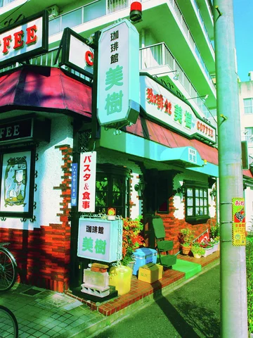 Green signs and awnings decorate a red brick cafe entrance crowded with plants.
