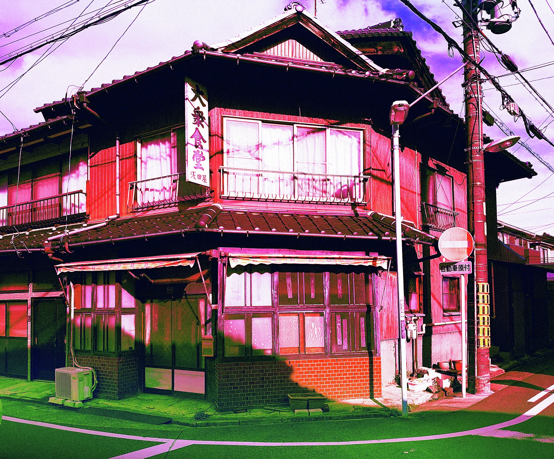 A red wooden corner building has layered tiled roofs and curtained windows beneath tangled overhead wires.