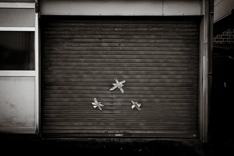 Three pale star-shaped patches mark a closed dark metal shutter in black and white.
