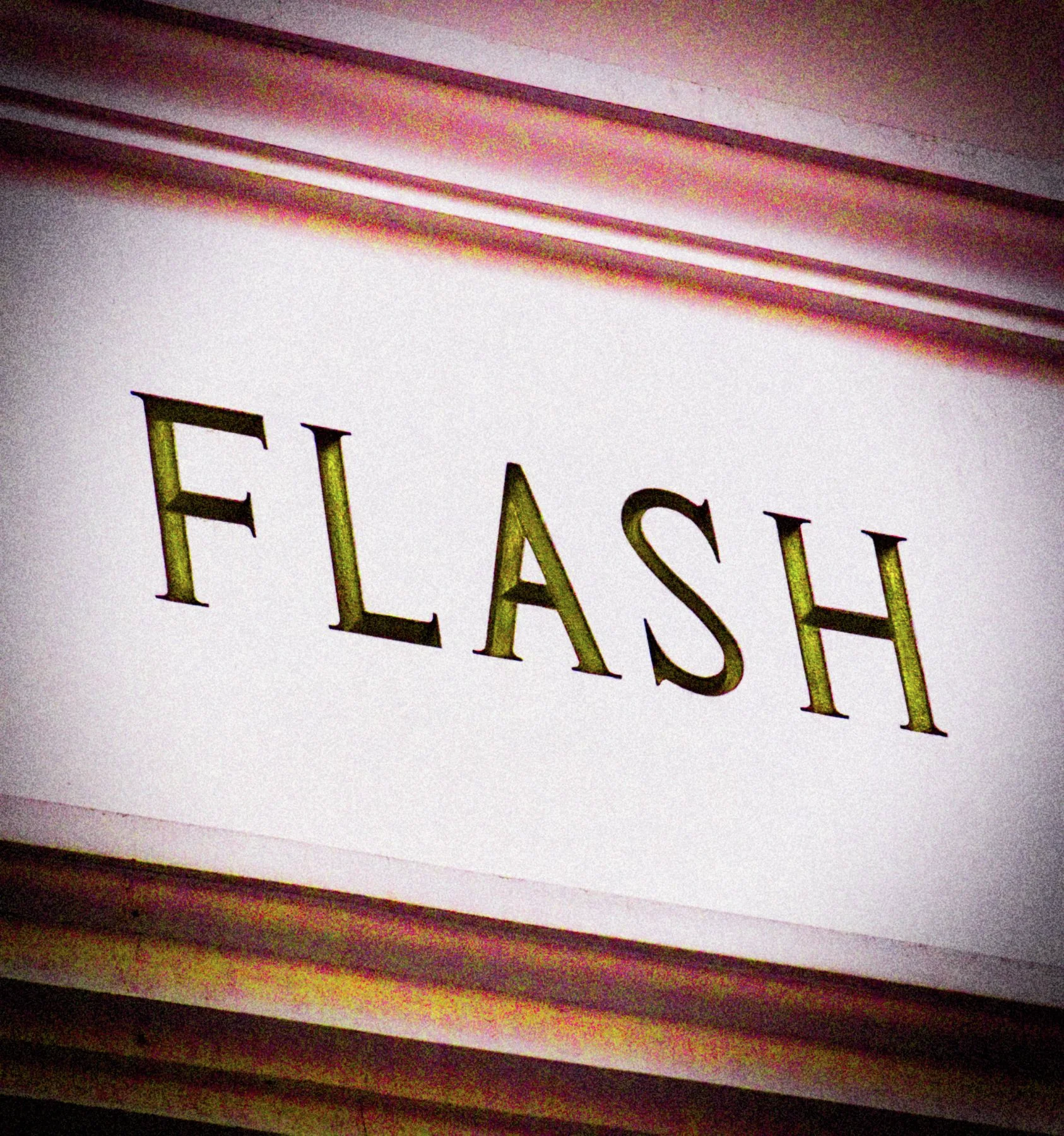 Dark FLASH lettering spans a pale rectangular sign within a weathered metallic border.