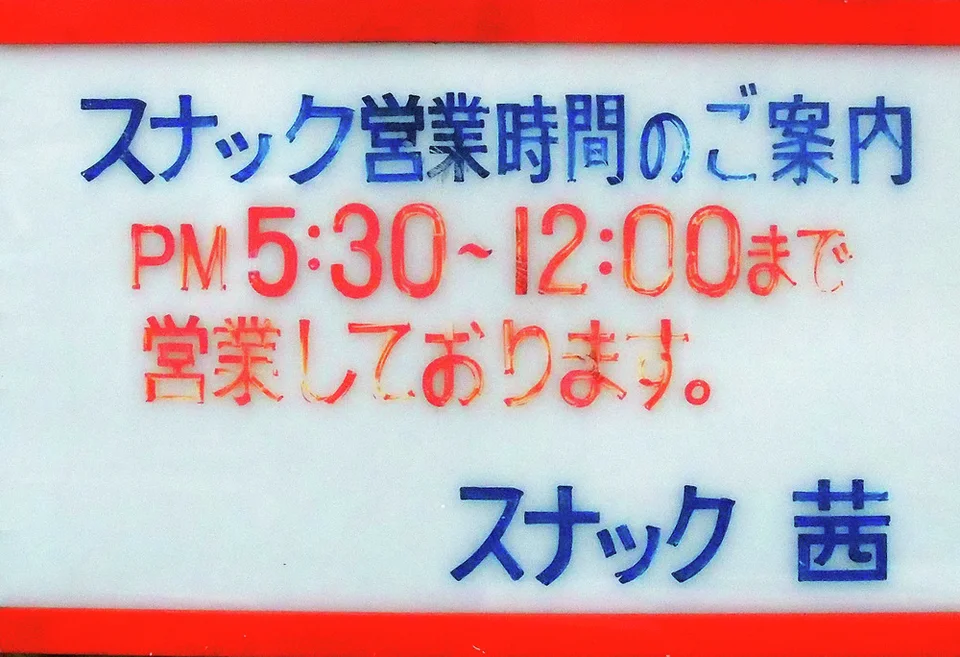 Blue Japanese lettering and red opening hours fill a pale rectangular sign bordered in red.