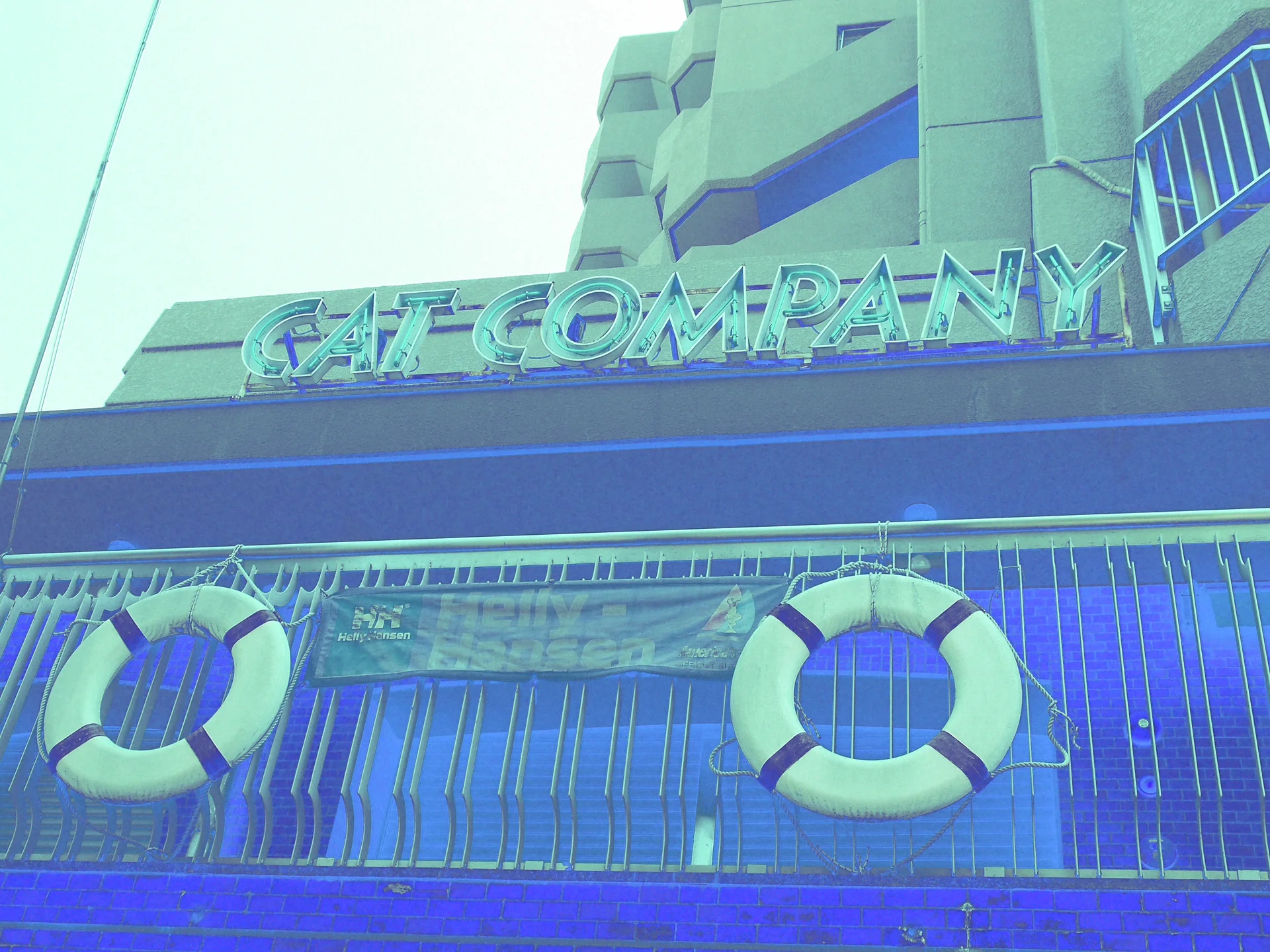 CAT COMPANY lettering tops a blue storefront railing decorated with two pale life rings.