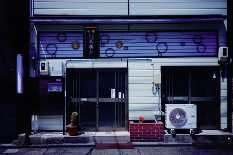 Circular decorations cover a blue-toned facade above glass doors and an outdoor air conditioner.