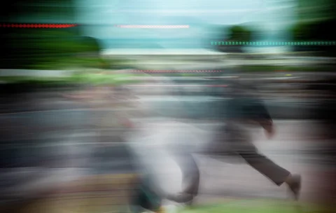 A pedestrian's legs stretch across a street scene smeared into horizontal blue and green streaks.
