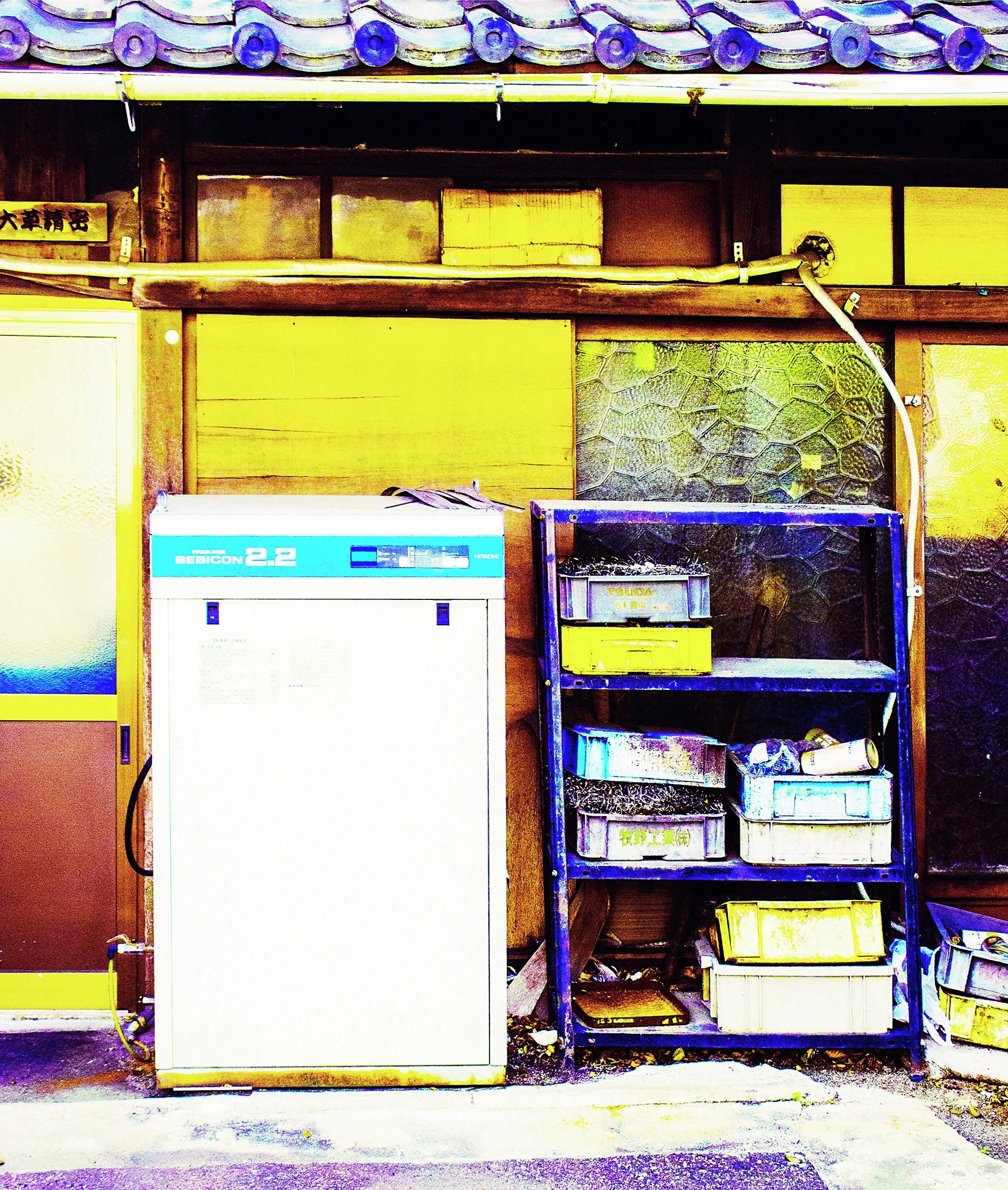A tall white cabinet and open storage shelves stand beneath weathered wooden panels and blue roof tiles.