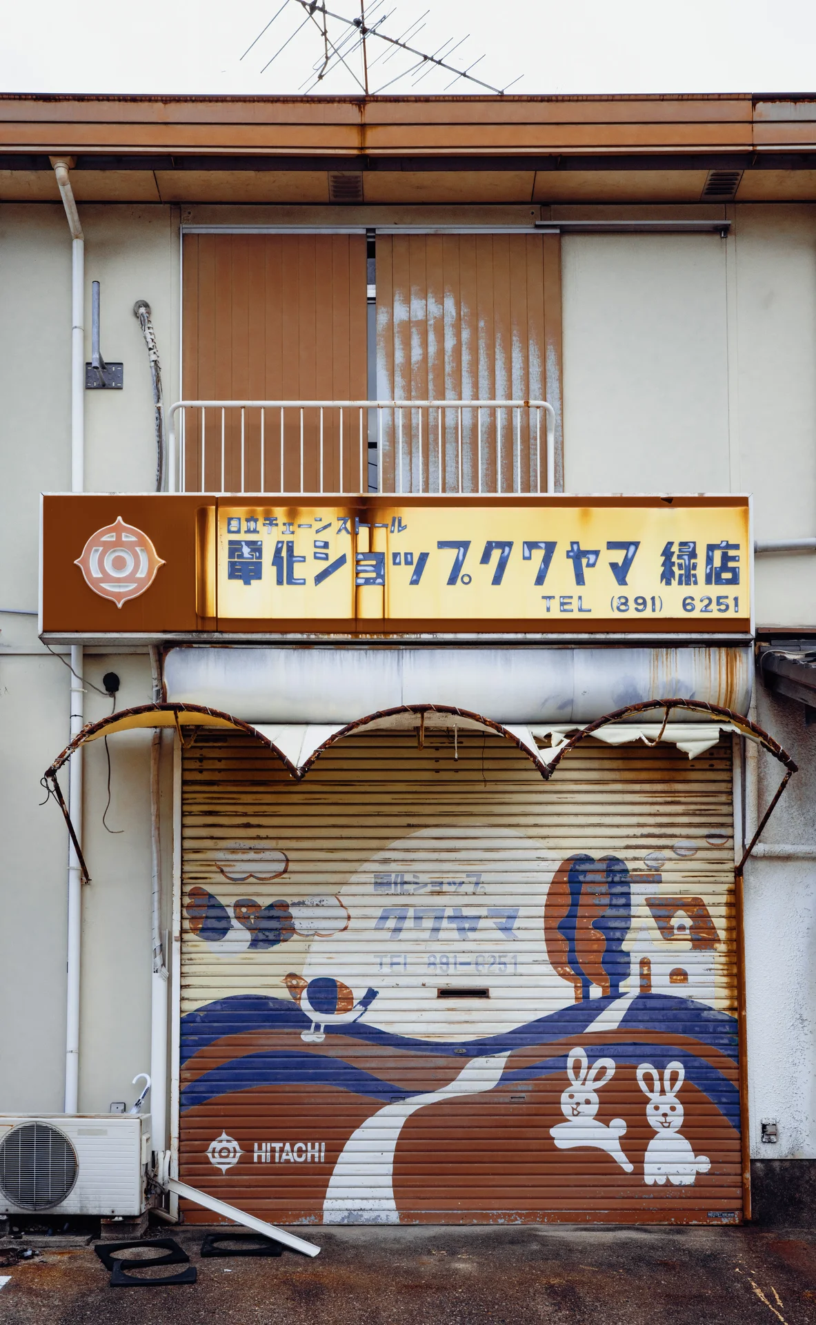 A painted cartoon face decorates a closed shop shutter beneath a sign and upstairs balcony.