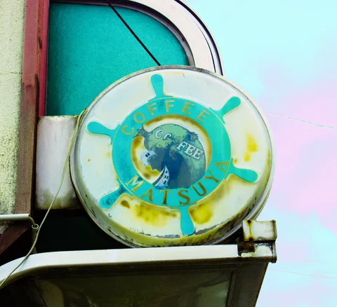 A weathered circular coffee sign with turquoise wheel-like decoration projects beside an arched window.