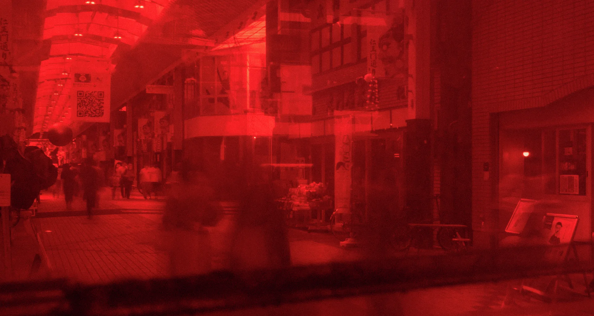 Street buildings and faint pedestrian silhouettes appear through a strongly red-tinted reflective window.