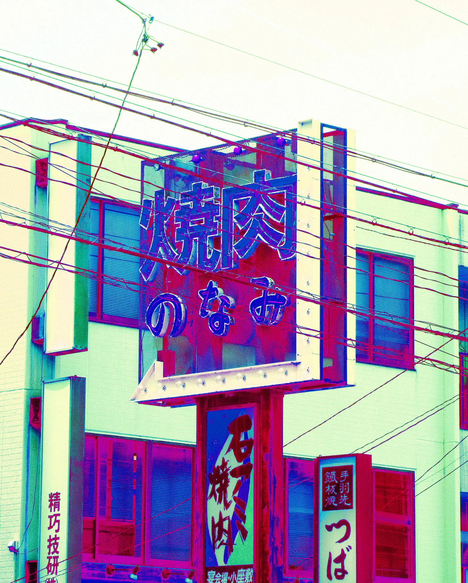 A large framed restaurant sign projects above smaller vertical signs behind a web of overhead cables.