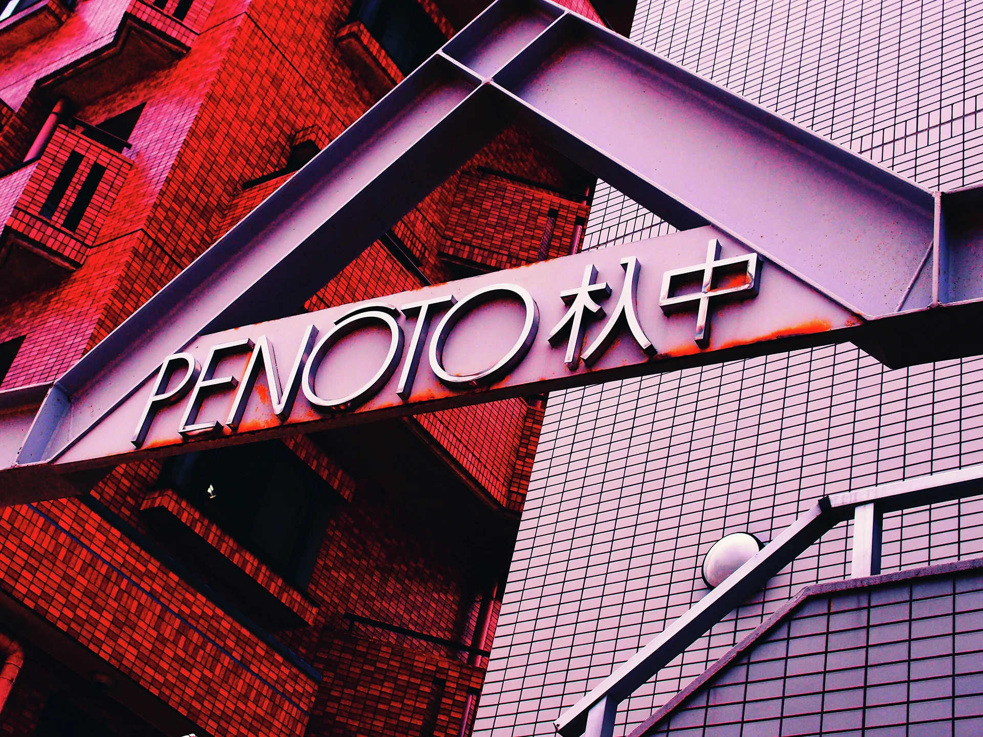 Large lettering spans a triangular metal canopy between red brick and pale tiled building walls.