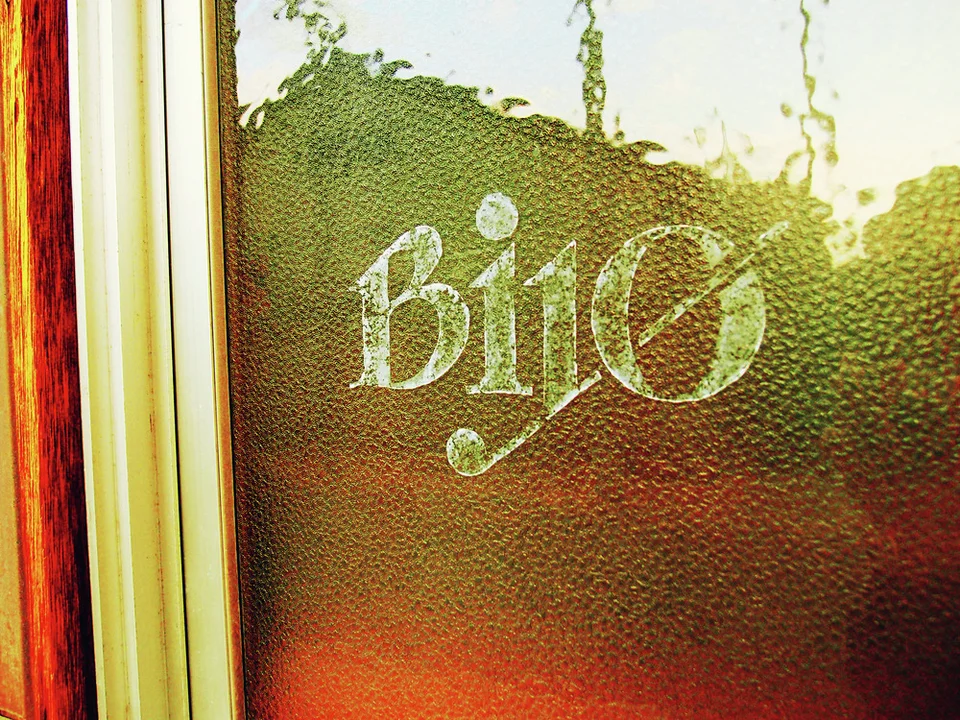 Pale Bijo lettering appears on textured glass beside reddish wooden trim.