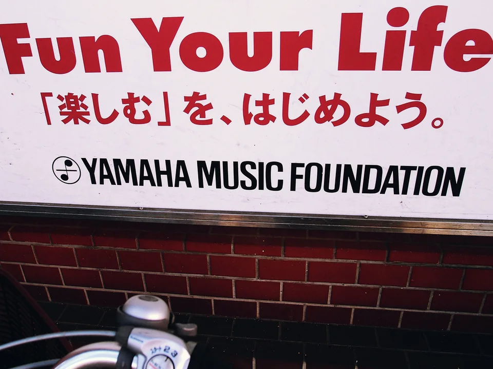 Bold red Fun Your Life text sits above black YAMAHA MUSIC FOUNDATION lettering on a pale sign.