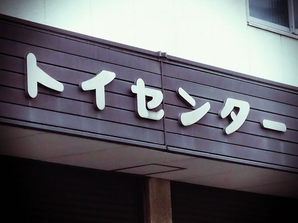 Raised pale Japanese characters cast shadows across a dark purple horizontal shop fascia.