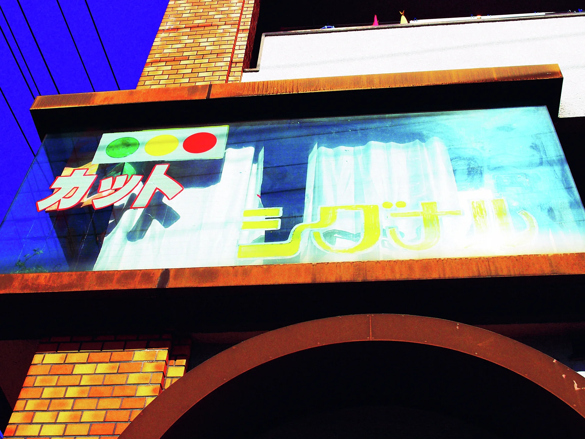 A faded blue sign with colored circles hangs above an arched brick entrance.
