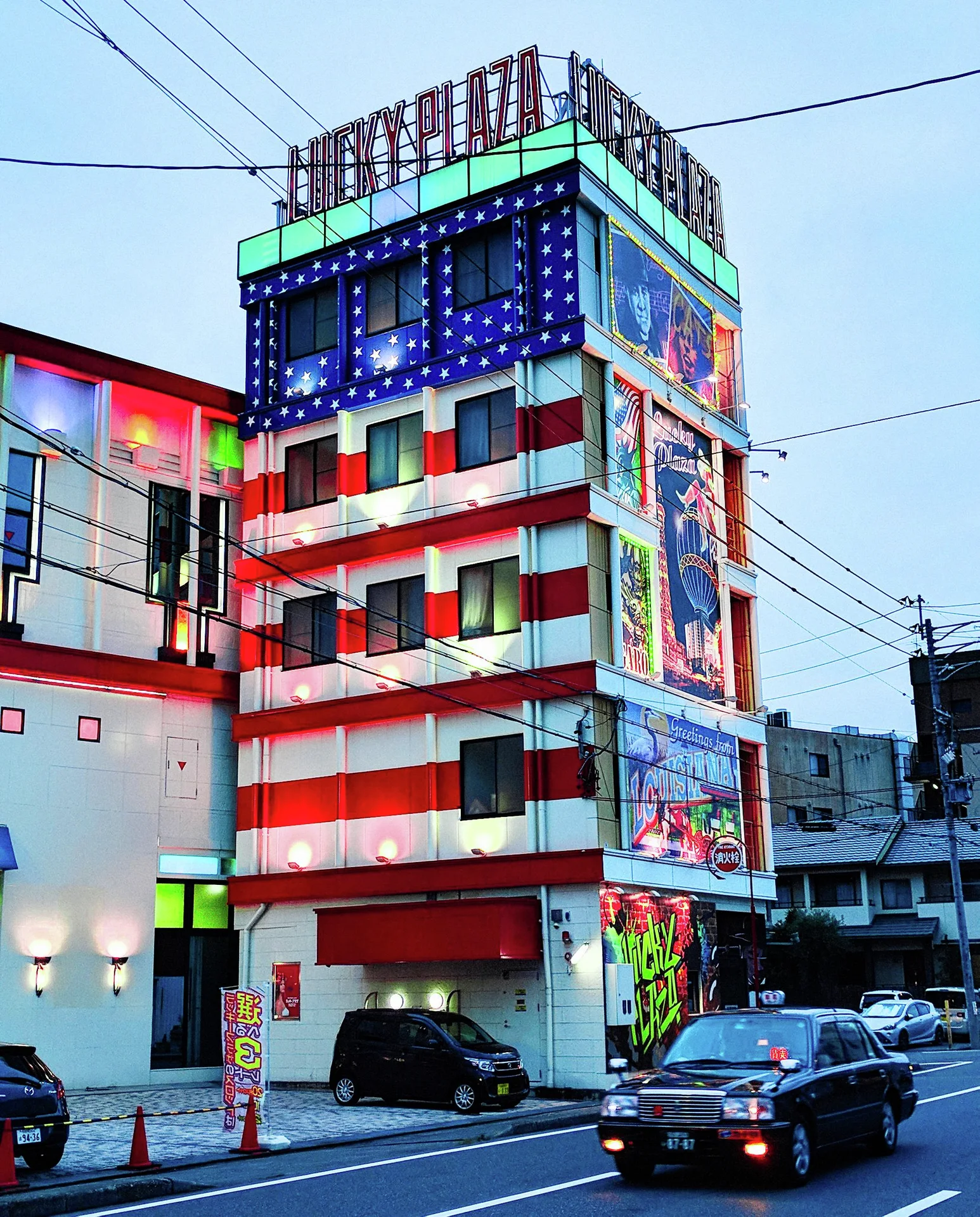 A narrow tower painted in red and white stripes carries colorful panels and blue lights above passing vehicles.