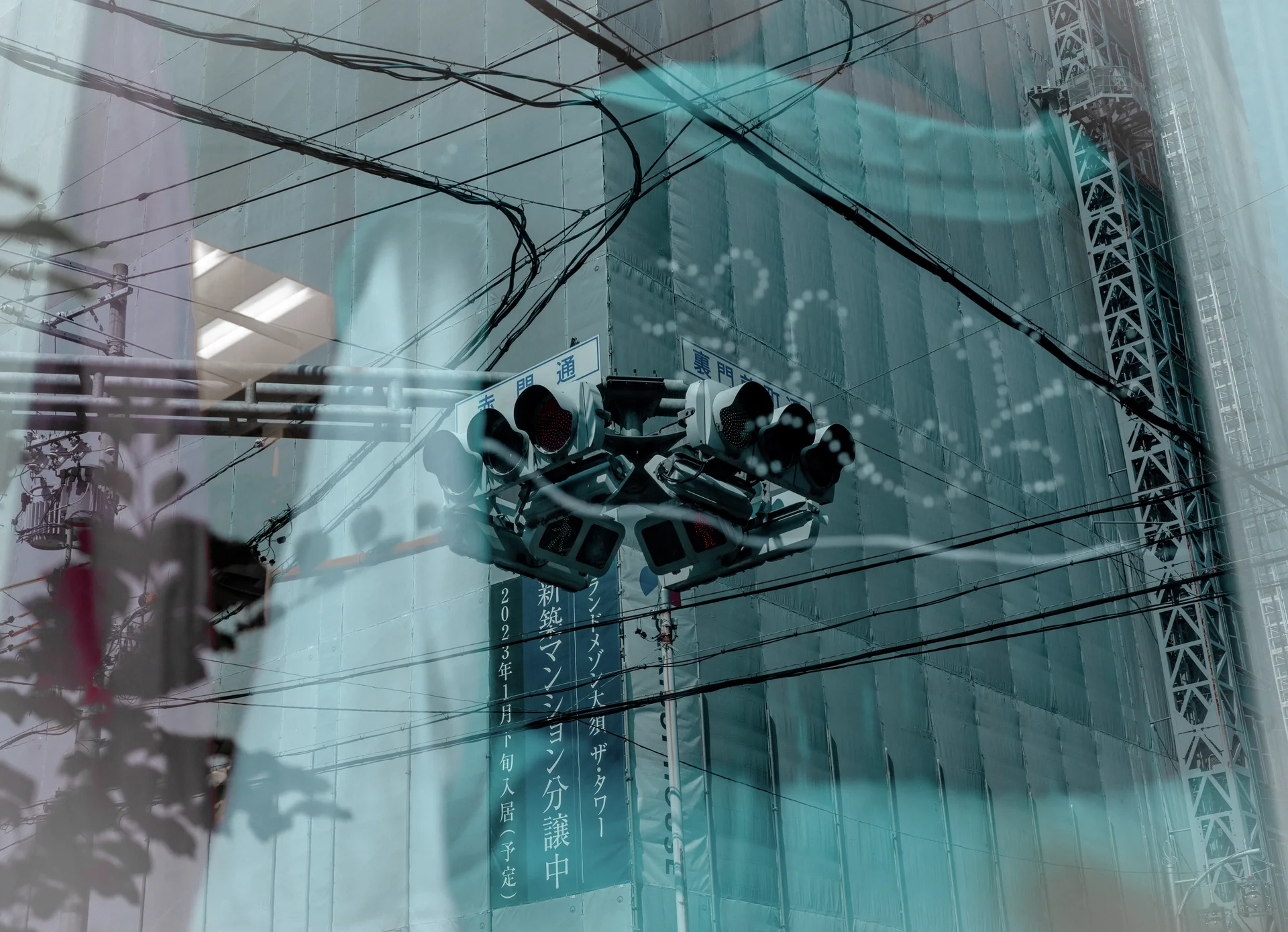 Overhead wires and clustered loudspeakers overlap a blue-covered construction facade through reflections in glass.