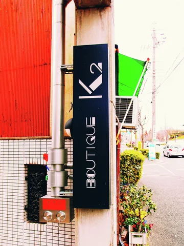 A black vertical BOUTIQUE sign with a white hanger symbol projects beside a bright green awning.