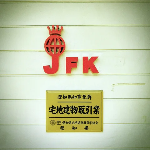 Red raised letters and a globe emblem sit above a gold rectangular plaque on pale siding.